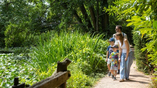 A family strolling by the lake at Baddesley Clinton, Warwickshire